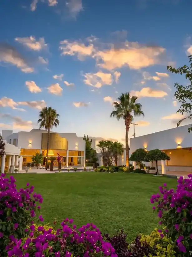 Jardines de Hacienda de Samotracia al atardecer con buganvilias y palmeras.