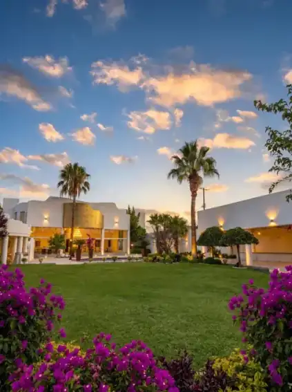 Jardines de Hacienda de Samotracia al atardecer con buganvilias y palmeras.